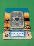 The 1oz .999 Silver Bar PAMP Star Of David features the Star of David and rests on packaging depicting Jerusalem's Western Wall, with a label displaying "Star of David" in both English and Hebrew.