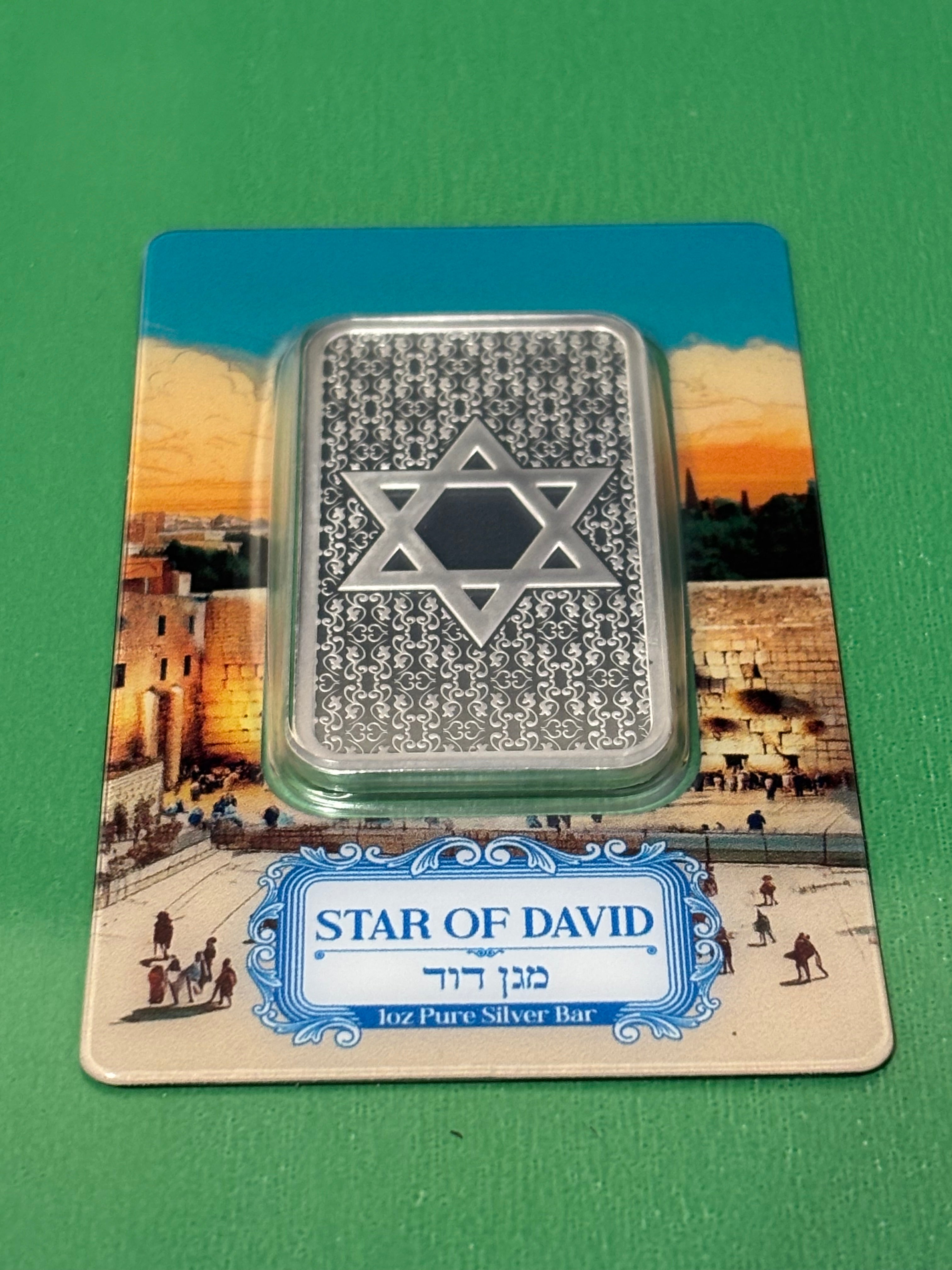 The 1oz .999 Silver Bar PAMP Star Of David features the Star of David and rests on packaging depicting Jerusalem's Western Wall, with a label displaying "Star of David" in both English and Hebrew.
