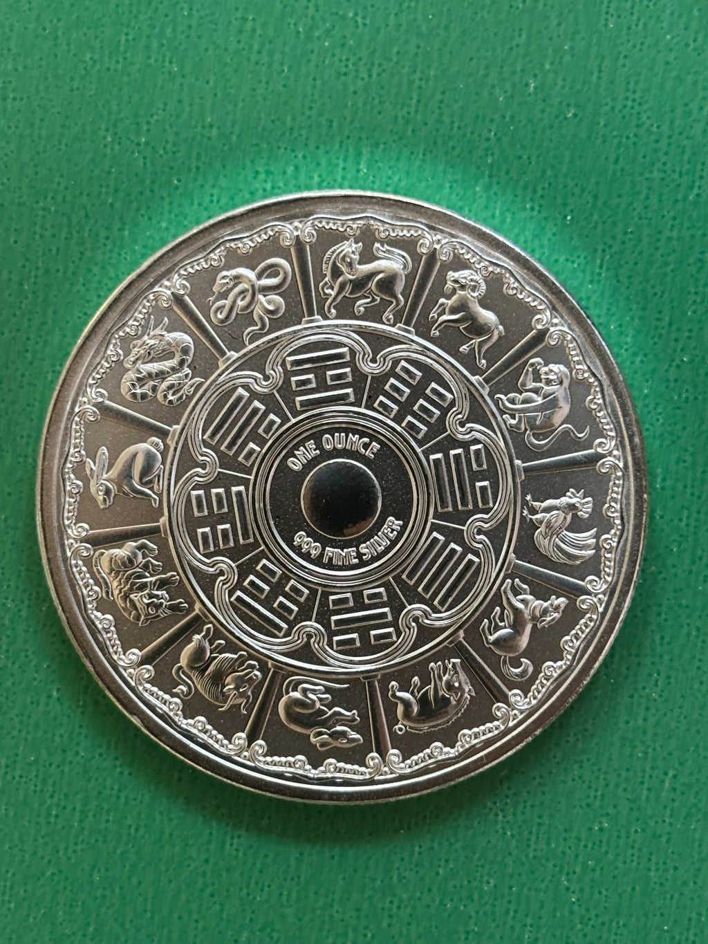 The 1oz .999 Silver Year Of The Snake 2025 coin features the twelve Chinese zodiac animals around the edge, detailed patterns, and “ONE OUNCE 999 FINE SILVER” at the center on a green background.