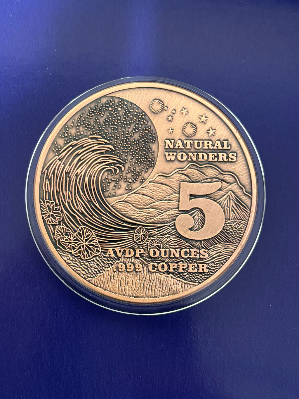 A 1oz ADVP Copper Round features the Amazon Rainforest with text: “NATURAL WONDERS,” “1 AVDP OUNCE,” and “.999 COPPER” displayed against a blue background.