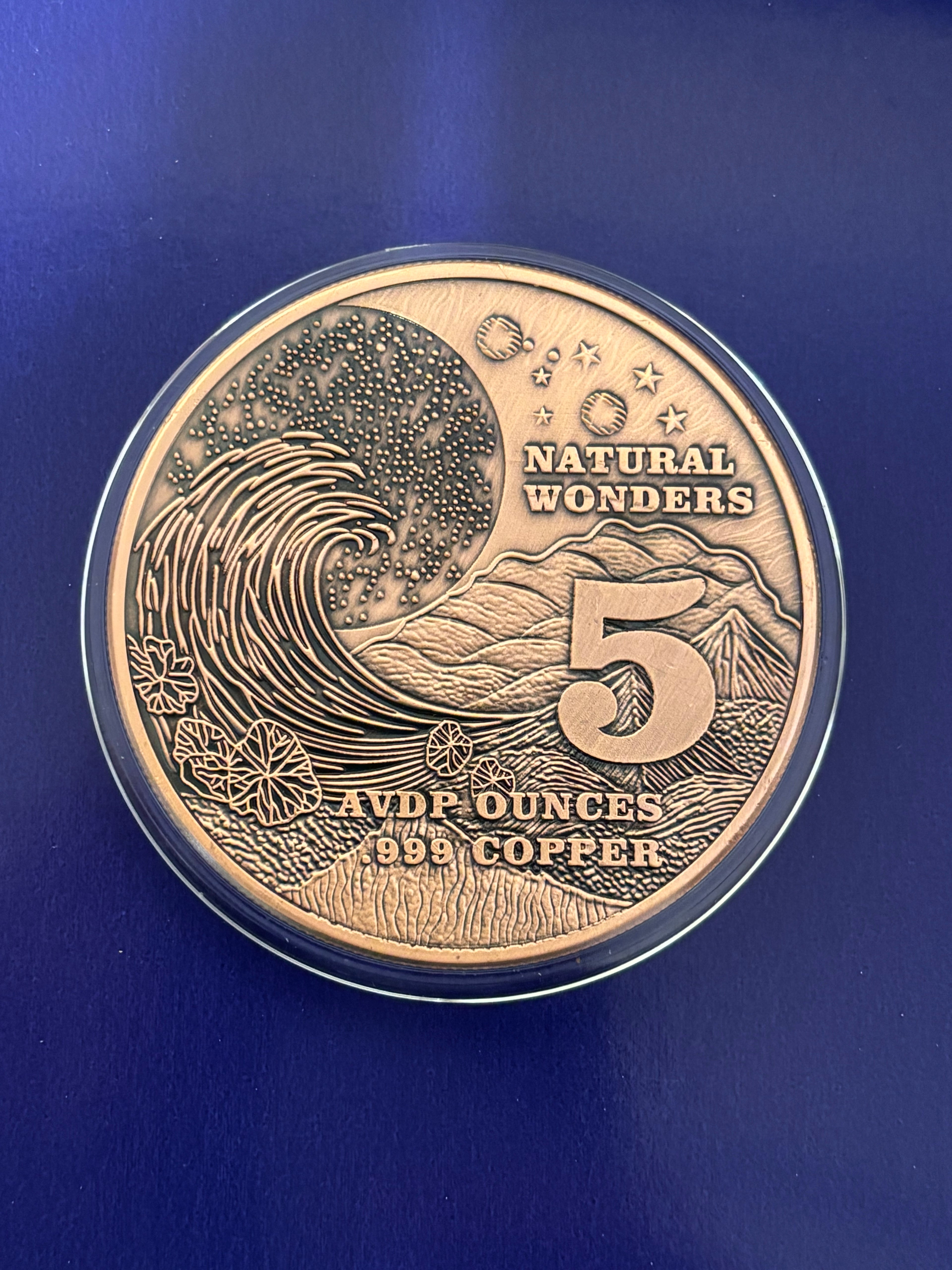 A 1oz ADVP Copper Round features the Amazon Rainforest with text: “NATURAL WONDERS,” “1 AVDP OUNCE,” and “.999 COPPER” displayed against a blue background.